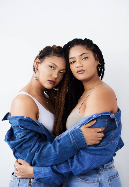 They complete each others look. Studio shot of two beautiful young women posing against a grey background. - Foto, imagen