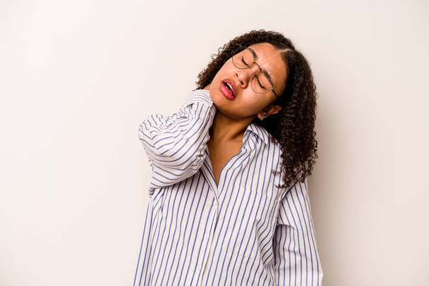Νεαρή Αφροαμερικανή γυναίκα απομονωμένη σε λευκό φόντο που υποφέρει από πόνο στον αυχένα λόγω καθιστικού τρόπου ζωής. - Φωτογραφία, εικόνα