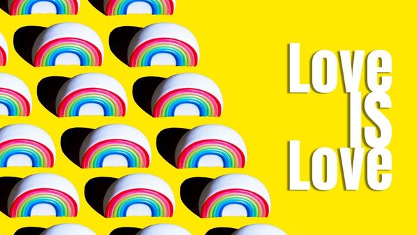 Pattern of Figure of a rainbow on a yellow background with the words Love is Love printed on it. LGBT love concept - Fotografie, Obrázek