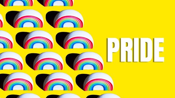 Рисунок радуги на жёлтом фоне со словом Pride, напечатанным на нём. Концепция гордости ЛГБТ - Фото, изображение
