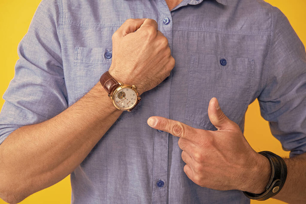 recadré homme pointant doigt sur main montre sur fond jaune, le temps - Photo, image
