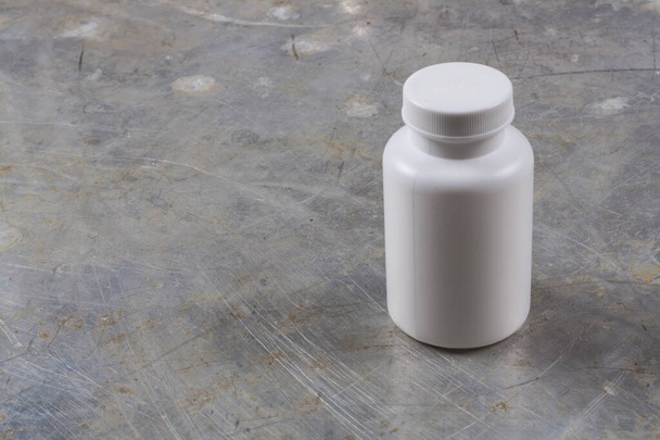 White plastic jar for medicines or pills on a gray iron background, there is a place for an inscription or your logo - 写真・画像