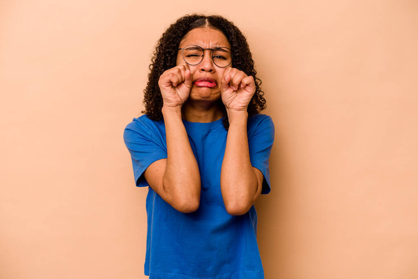 Joven mujer afroamericana aislada sobre fondo beige gimiendo y llorando desconsoladamente. - Foto, Imagen