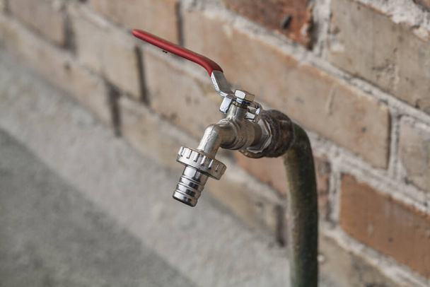 Aluminum faucet to turn on the water with a red switch and water the garden or greenhouse plants - Photo, image