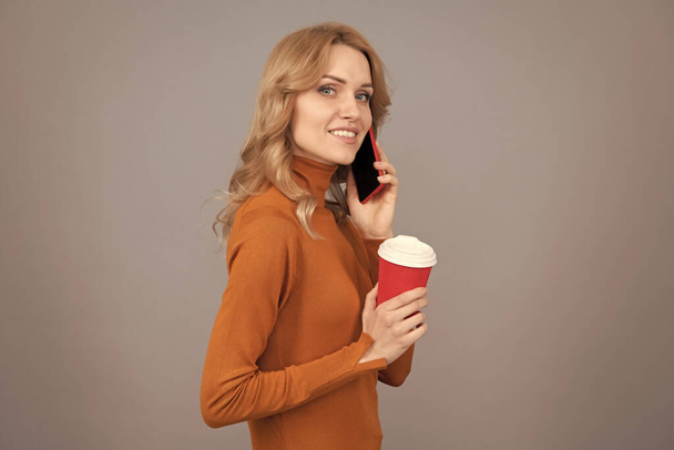 Kobieca rozmowa przez telefon z kubkiem. Komunikacja mobilna. Mobilna kawa lub espresso w dowolnym miejscu. - Zdjęcie, obraz
