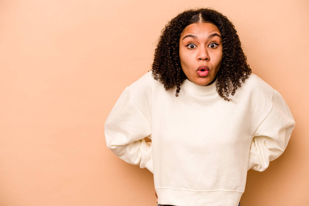 Young African American woman isolated on beige background being shocked because of something she has seen. - Photo, Image