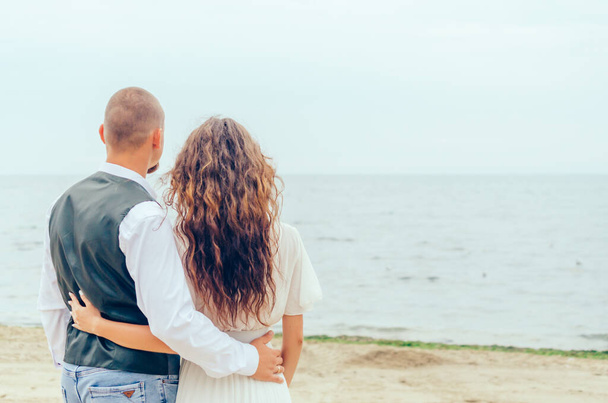 мужчина и женщина стоят на берегу и смотрят на море - Фото, изображение