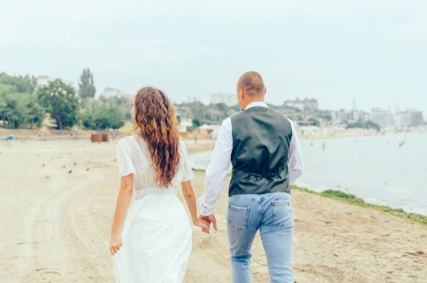 man and woman running on the beach in wedding clothes - 写真・画像