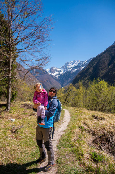 Der Vater umarmt seine Tochter beim Spaziergang auf einer Waldwiese. Aktives Familienleben im Freien. - Foto, Bild