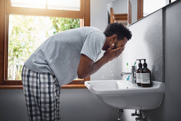 Osvěžuju se. Vystřižený záběr pohledný mladý muž mytí obličeje v koupelně doma. - Fotografie, Obrázek