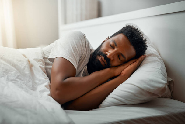 Спит на выходных. Обрезанный снимок красивого молодого человека, спящего в постели дома. - Фото, изображение