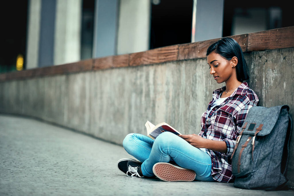 Mi lugar de estudio favorito. Fotografía de una joven estudiante leyendo un libro afuera en el campus. - Foto, imagen