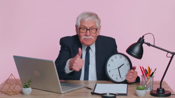 Senior usměvavý obchodník ukazuje čas na nástěnné kancelářské hodiny, ok, palec nahoru, dobře schvalují úspěch - Záběry, video