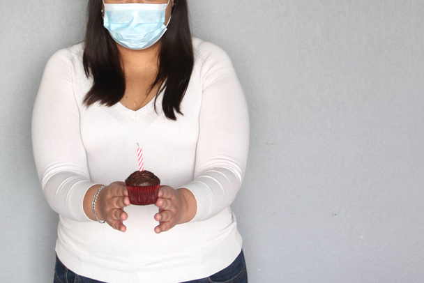 mujer latina con pelo negro con máscara de protección, celebra cumpleaños con pastel en casa debido a la cuarentena y nuevo covid-19 normal, - Foto, Imagen