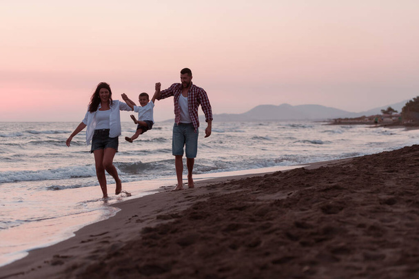 The family enjoys their vacation as they walk the sandy beach with their son. Selective focus  - Φωτογραφία, εικόνα