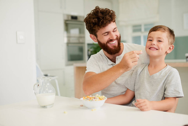 朝食はその日の最初の笑顔をもたらします。かわいい男の子と彼の父親のショットで一緒に家に朝食を持っている. - 写真・画像
