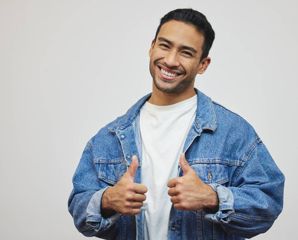 Two thumbs up for you. Cropped portrait of a handsome young man giving thumbs up in studio against a grey background. - Foto, Imagem