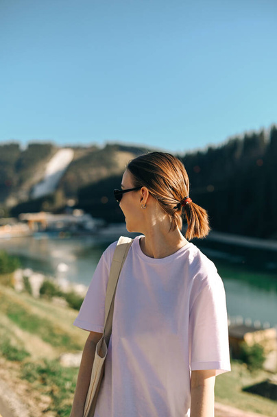 Позитивна жінка стоїть в горах на курорті в сонячний літній день під час прогулянок і огляду. Вертикальний
 - Фото, зображення