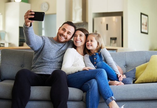 Nun haben diese Erinnerungen für immer. Aufnahme einer jungen Familie, die ein Selfie auf der heimischen Couch macht. - Foto, Bild