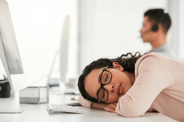 A quick nap wont hurt. Shot of a young female call center agent taking a nap at work. - Fotó, kép