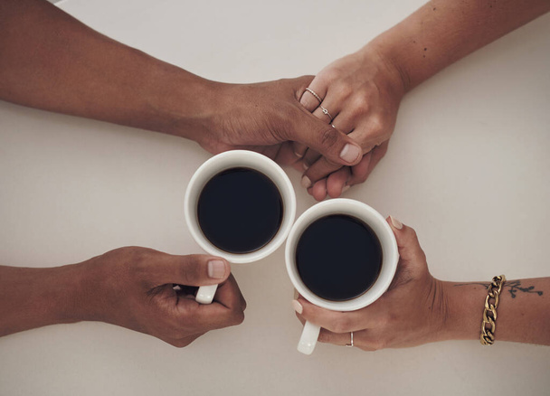 I have all the support I need from him and coffee. High angle shot of an unrecognizable couple sitting together and enjoying a cup of coffee while holding hands. - Photo, Image