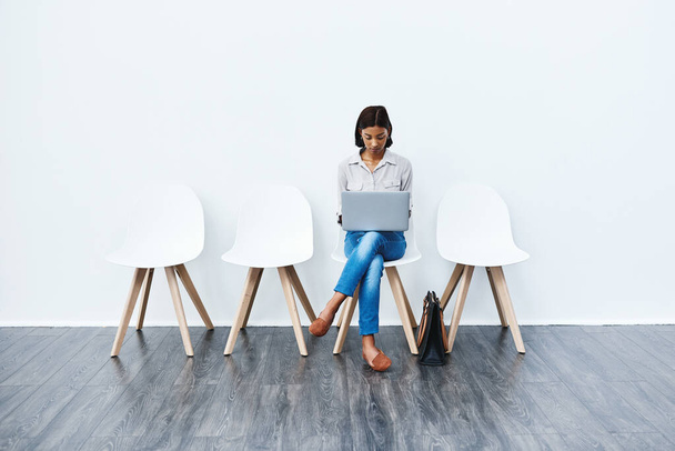 Blijf geconcentreerd en toegewijd aan je doelen. Full length studio shot van een aantrekkelijke jonge zakenvrouw zitten op een stoel en met behulp van haar laptop. - Foto, afbeelding