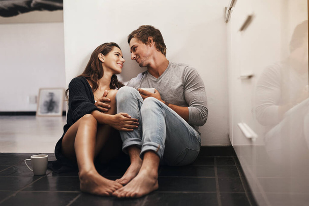 I feel at home in your eyes. Shot of an affectionate young couple sitting on the kitchen floor. - Foto, Bild