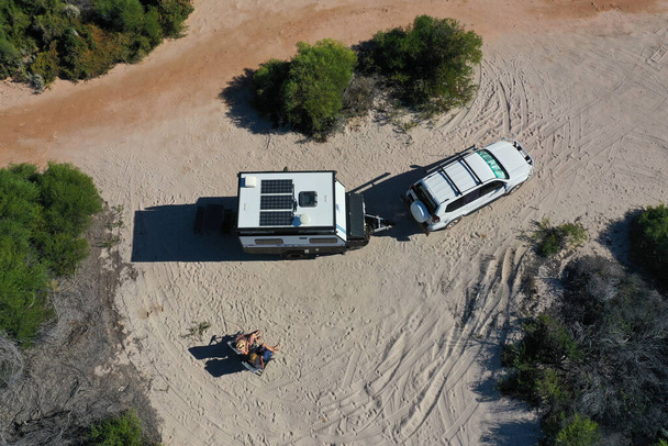 Australisches Paar entspannt sich während eines Strandurlaubs mit Geländewagen und Wohnwagen auf einer Sanddüne im Outback von Westaustralien. - Foto, Bild