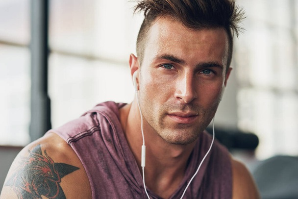 His serious about fitness. Shot of a handsome young man at the gym. - Photo, Image