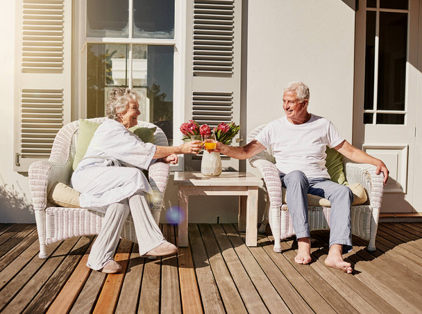 Heres to more mornings like this. Shot of a happy senior couple toasting with juice on the patio at home. - Fotó, kép