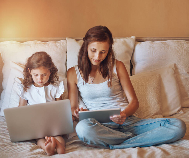 Rentoutua vempaimiensa kanssa. Laukaus pieni tyttö käyttää kannettavaa tietokonetta ja hänen äitinsä käyttäen digitaalista tablettia kotona. - Valokuva, kuva