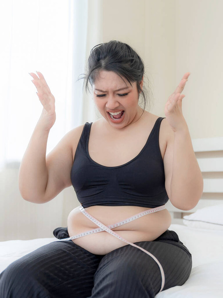 толстухи азиатского происхождения, толстушка, толстушка, лишний вес несчастный измерения ее талии в спальне - женщина диета образ жизни избыточный вес концепция проблемы - Фото, изображение
