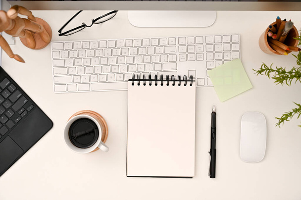 Modern white office desk workspace with empty spiral notepad mockup, coffee cup, keyboard and stationery. top view - Photo, Image