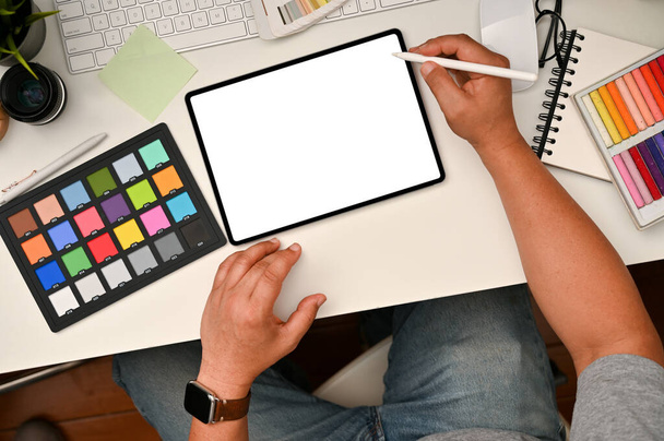 Graphic designer workspace concept, Male graphic designer or photo editor using digital tablet at his office desk. colour checker, stationery and stuff on white table, top view. - Photo, image