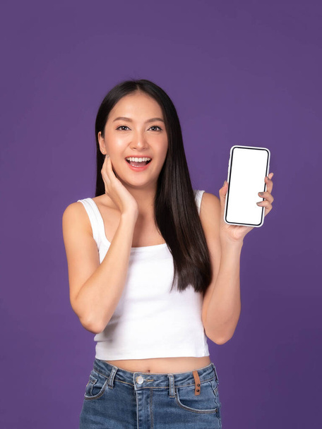 Beautiful Asian brunette woman cute girl in white tank top ,Excited surprised girl showing smart phone with blank screen , white screen isolated purple background , Mock Up Image - Φωτογραφία, εικόνα