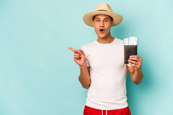 Young caucasian traveler man holding passport isolated on blue background pointing to the side - Foto, Imagem