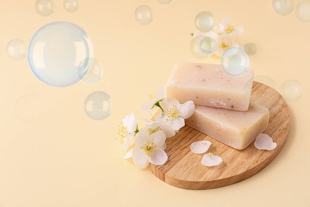 Board with soap bars and flowers on light color background - Fotó, kép