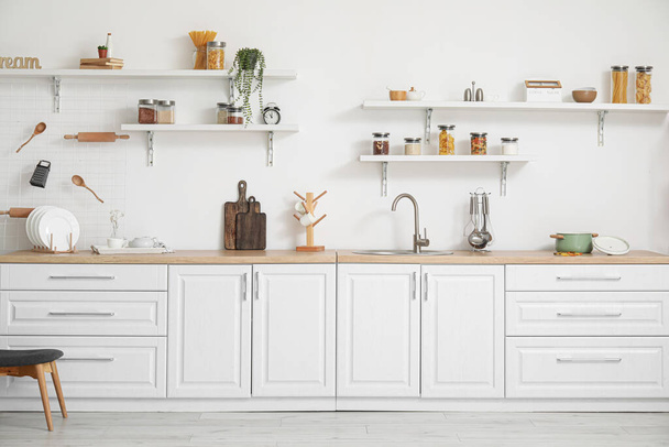 Інтер'єр світлої кухні з білими прилавками та посудом
 - Фото, зображення