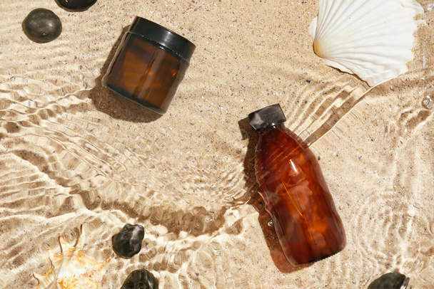 Cosmetic products and spa stones in water on sand - Photo, image