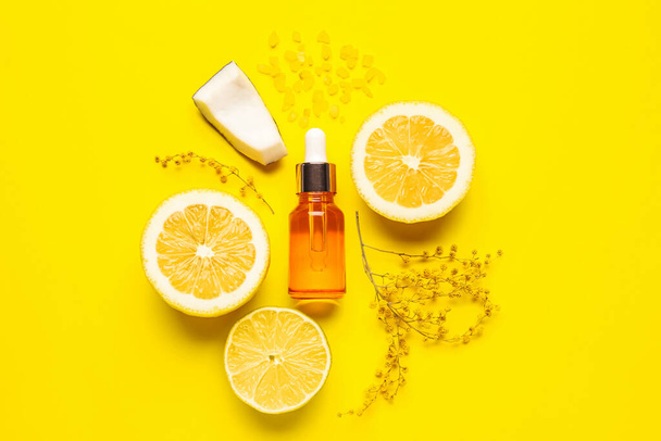 Bottle of natural serum with lemons, coconut, sea salt and flowers on yellow background - Foto, afbeelding