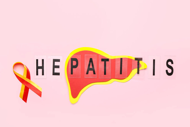 Лента осведомленности со словом HEPATITIS и бумажной печенью на розовом фоне - Фото, изображение