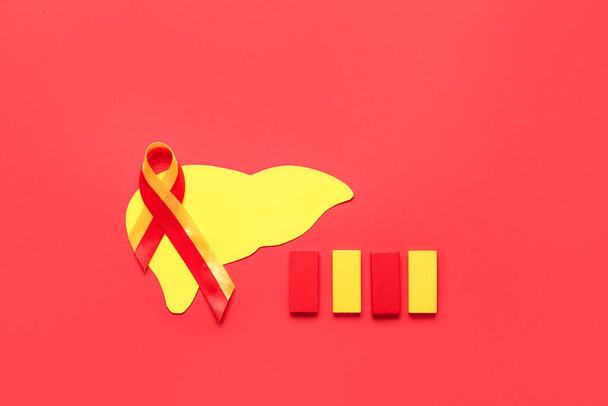 Awareness ribbon with paper liver and blocks on red background. Hepatitis concept - 写真・画像
