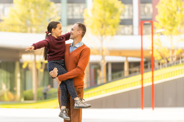 Iloista nuorta isää pienen tyttärensä kanssa. Isä ja lapsi leikkivät ulkona yhdessä syyspuistossa. Isä lapsensa kanssa nauraa ja nauttii luonnosta - Valokuva, kuva