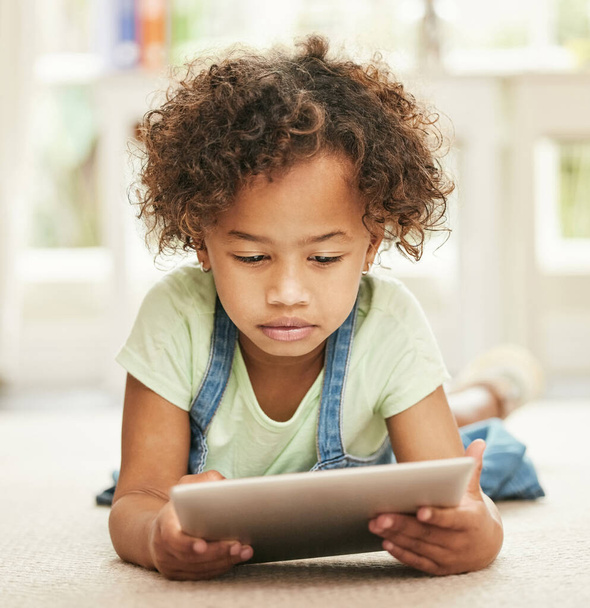 Sie nennen es Tablettenzeit. Aufnahme eines kleinen Mädchens mit einem digitalen Tablet zu Hause. - Foto, Bild