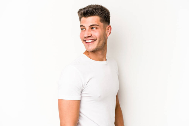 Jeune homme caucasien isolé sur fond blanc regarde de côté souriant, gai et agréable. - Photo, image