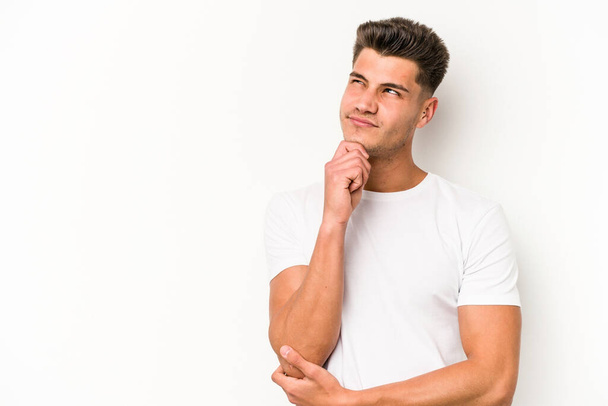 Young caucasian man isolated on white background relaxed thinking about something looking at a copy space. - Фото, изображение
