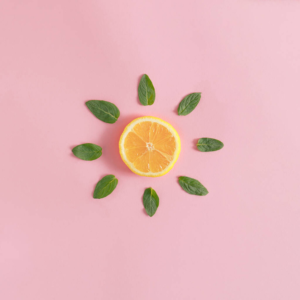 Shape of sun made of lemon slice and green mint leaves on bright pink background. Summer drink concept. Minimal flat lay aesthetic. - Zdjęcie, obraz