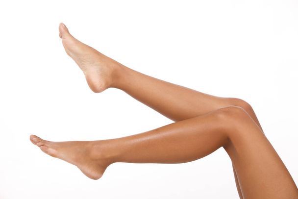 Загорелая кожа Женщина показывает ноги коленные ноги ноги голые, как части тела на белом фоне изолированы. В воздухе болтается нога - Фото, изображение