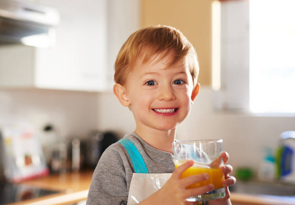 Jeugd dagen. Portret van een jonge jongen die thuis een glas sap drinkt. - Foto, afbeelding