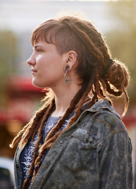 On top of the latest trends. Shot of a young woman with dreadlocks and piercings posing outdoors. - Foto, afbeelding